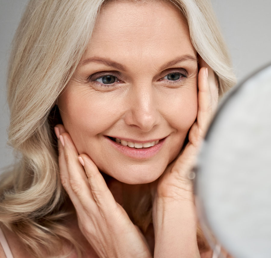 Woman admiring smoother skin after an Anti-Aging Facial.