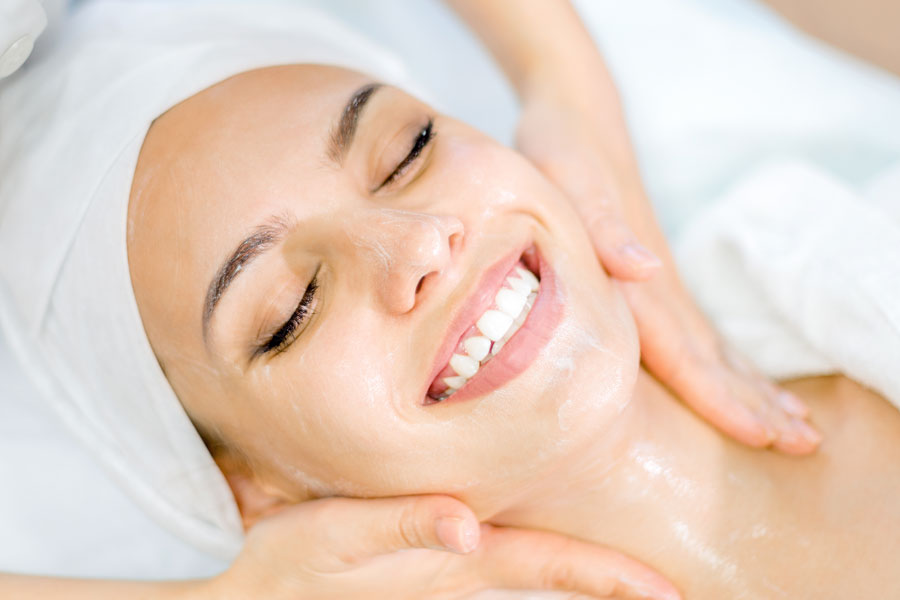 Smiling woman receiving facial treatment to relieve dehydration and dry skin.