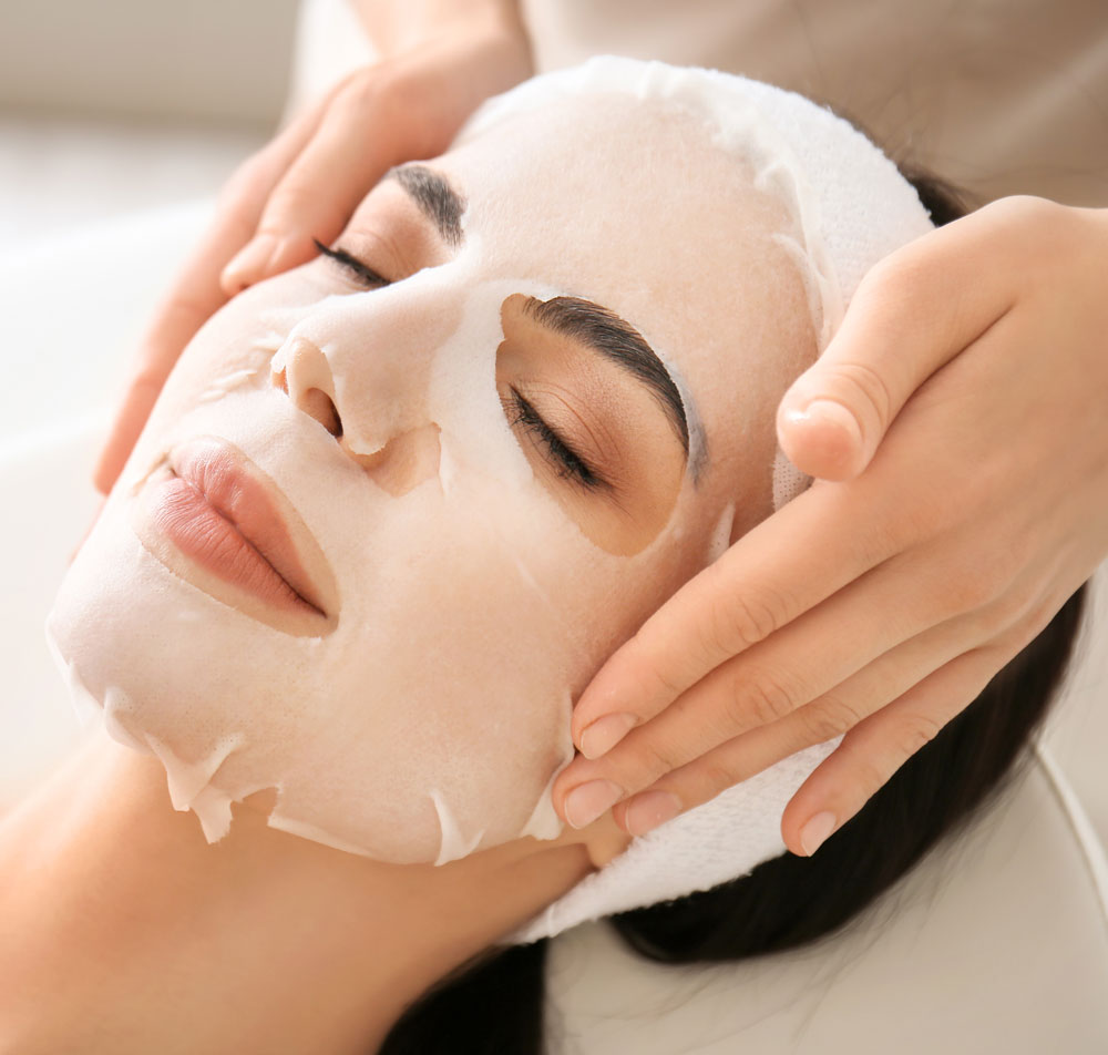 Woman receiving a facial mask treatment for hyperpigmentation and dark spots.