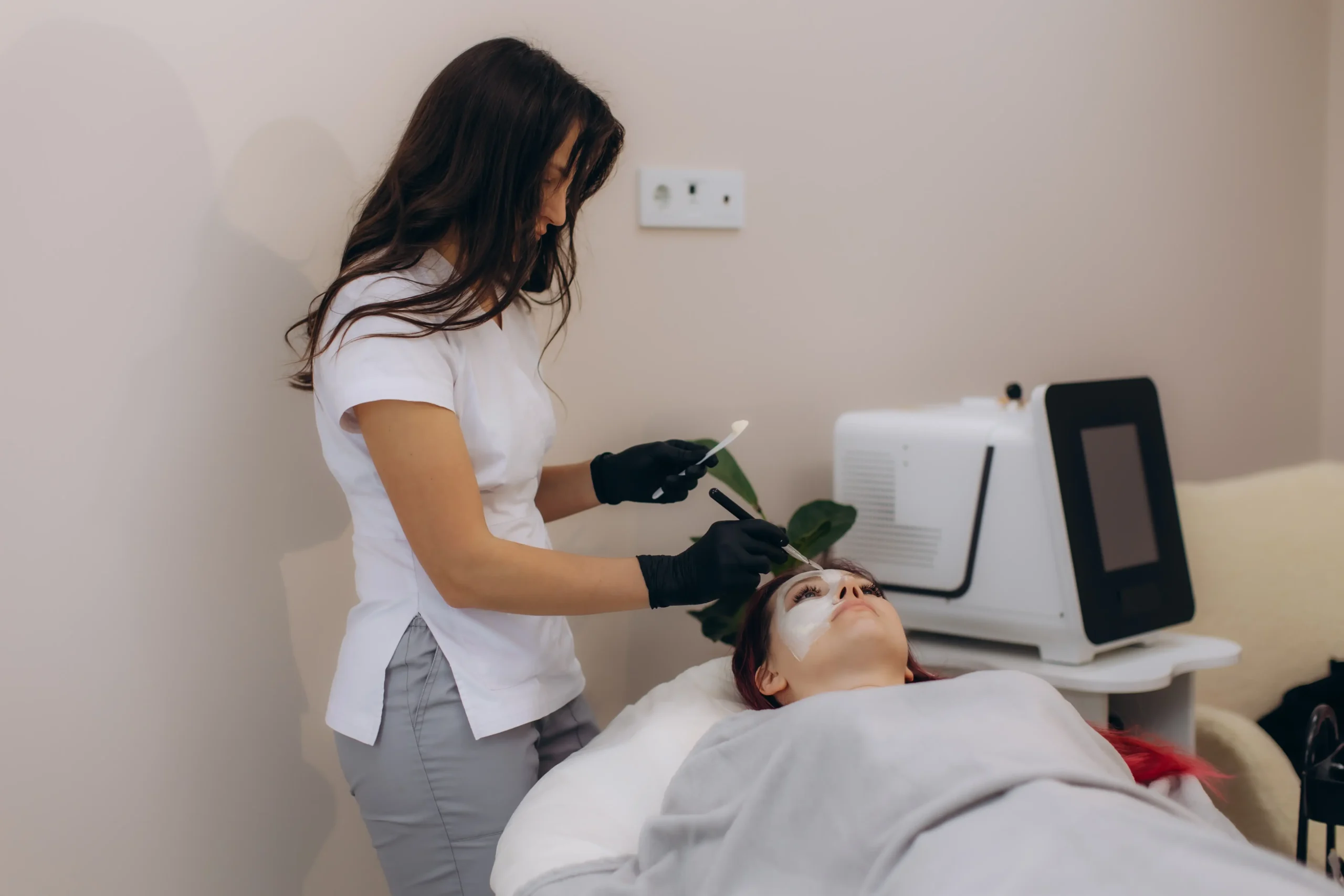 Practitioner applying product to client’s face during facial treatment